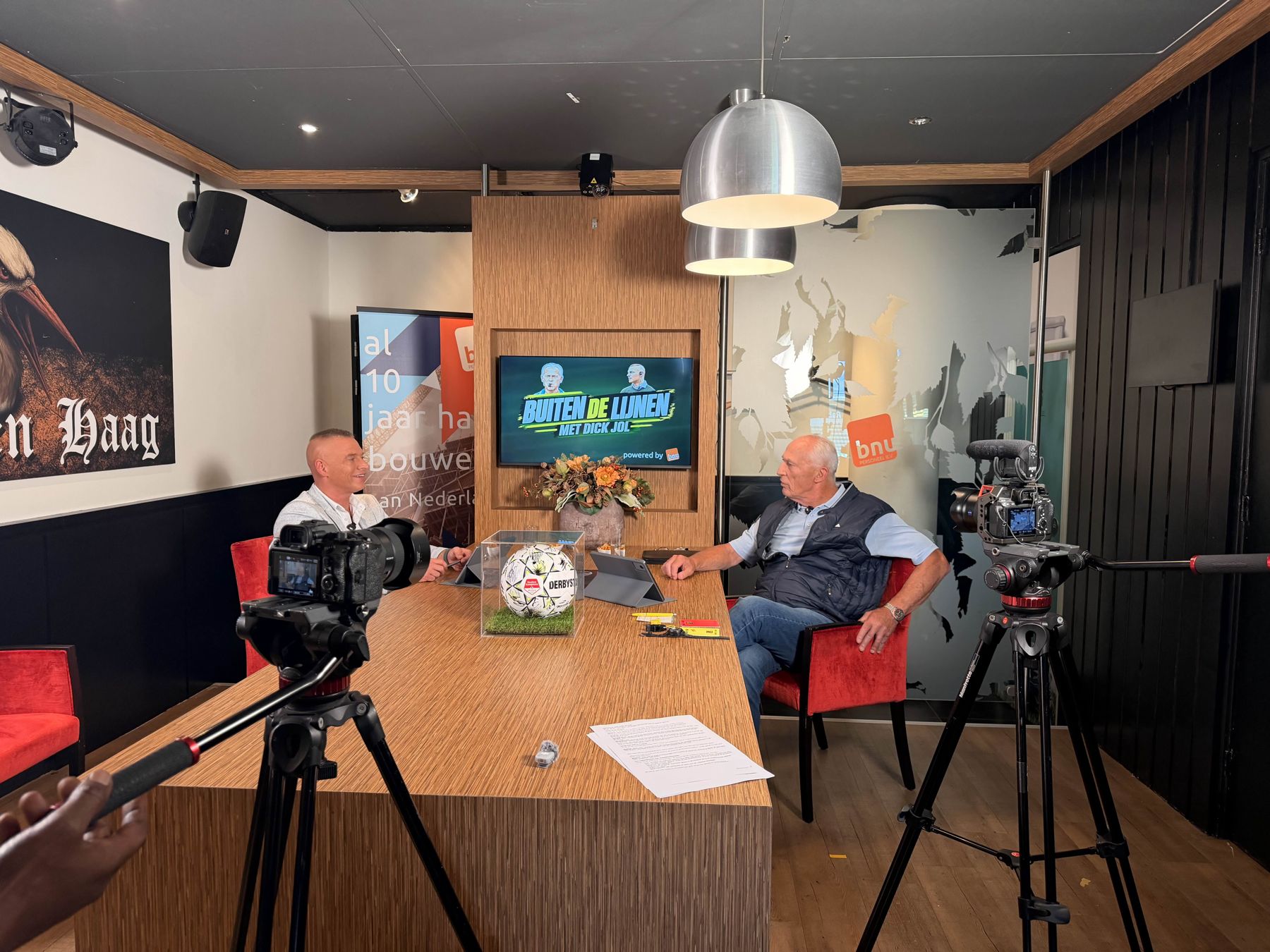 Marco Saat en Dick Jol aan tafel in de studio van Buiten de Lijnen, met camera's op de voorgrond
