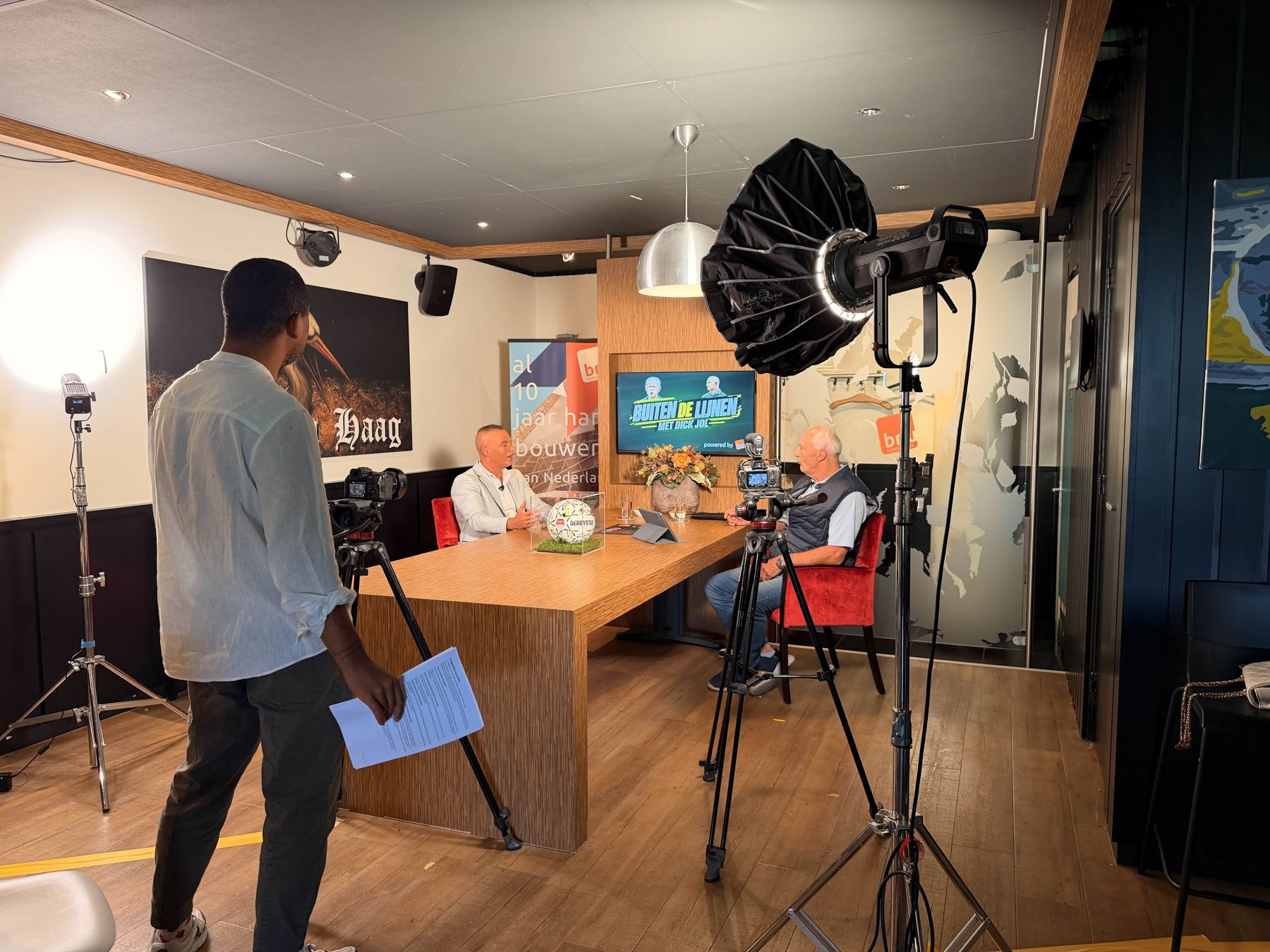 Achter de schermen: Marco Saat en Dick Jol aan tafel in de studio, met camera's en licht